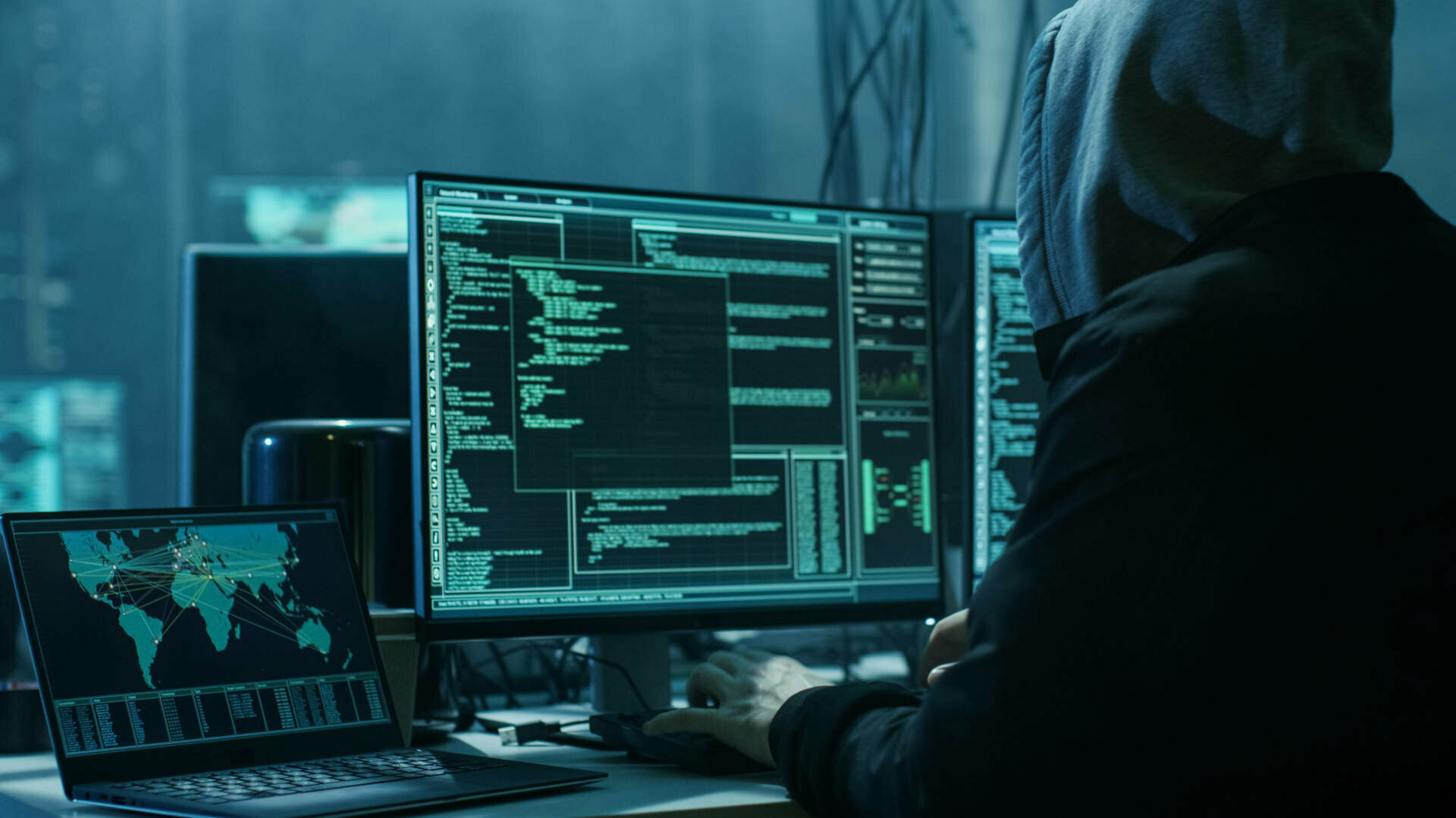 Hacker sitzt vor einem Bildschirm in einem dunklen Raum